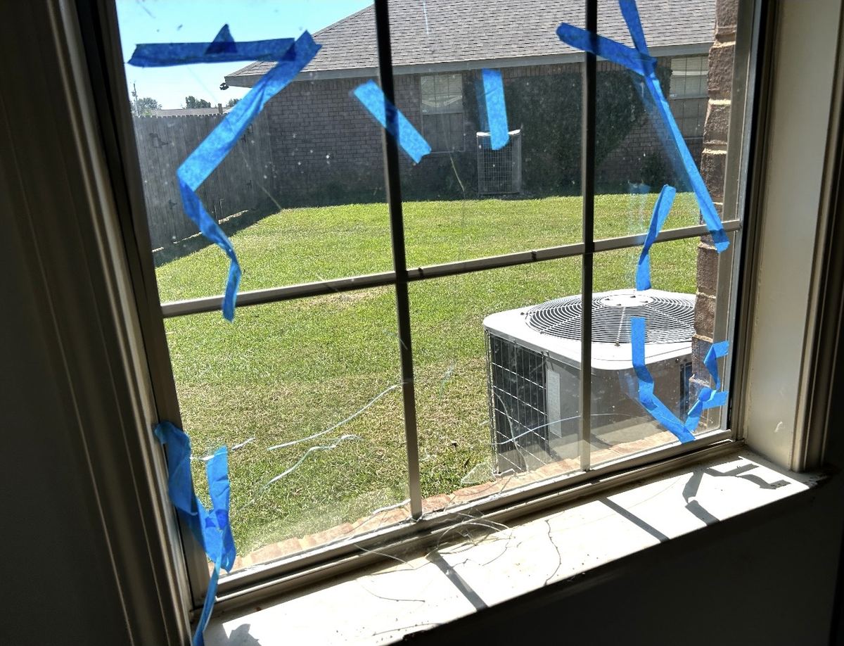 Before: cracked window glass taped with blue tape, close-up