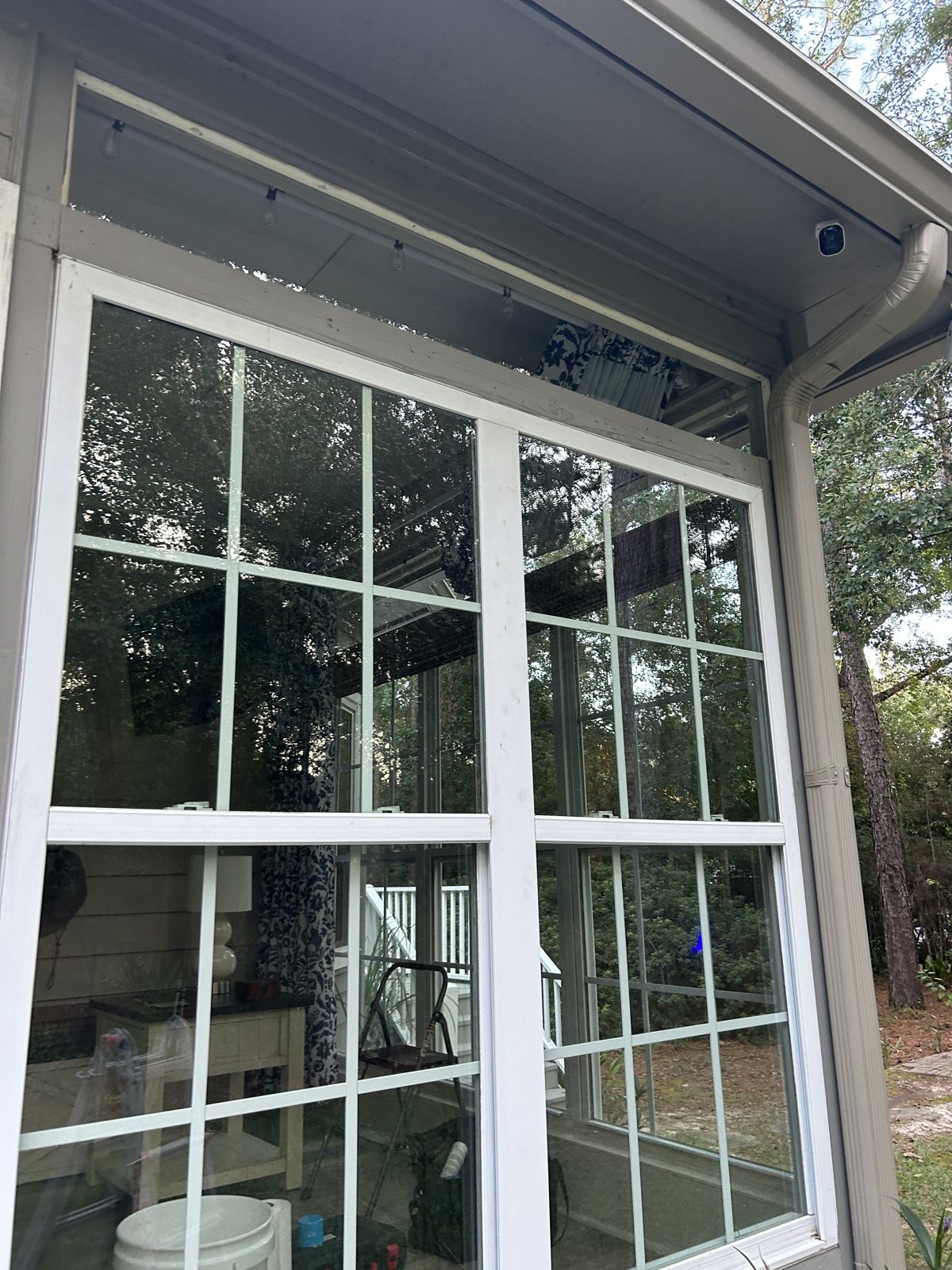 After: exterior view of a large white double window with new clear replacement glass installed in the existing frames