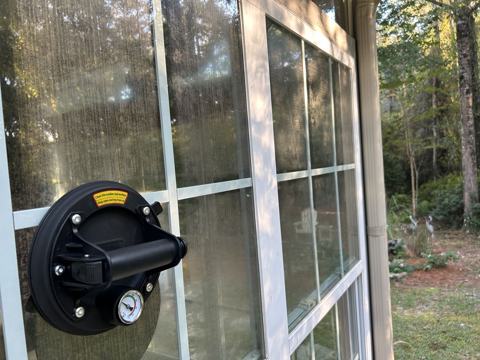 Before: foggy, failed-seal window glass with a suction lifter attached, ready for the glass to be replaced